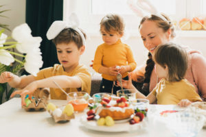 Family preparing eggs for Easter. Family with two sons wearing Bunnyâs Ears painting Easter eggs at home. Decorations for coloring eggs for holiday. Happy Easter concept.