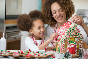 mother and daughter decorating gingerbread house