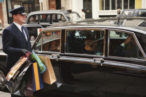 chauffeur holding shopping backs by vehicle