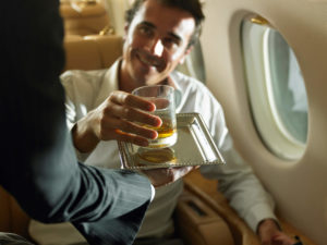 staff on private jet delivering drink to man aboard